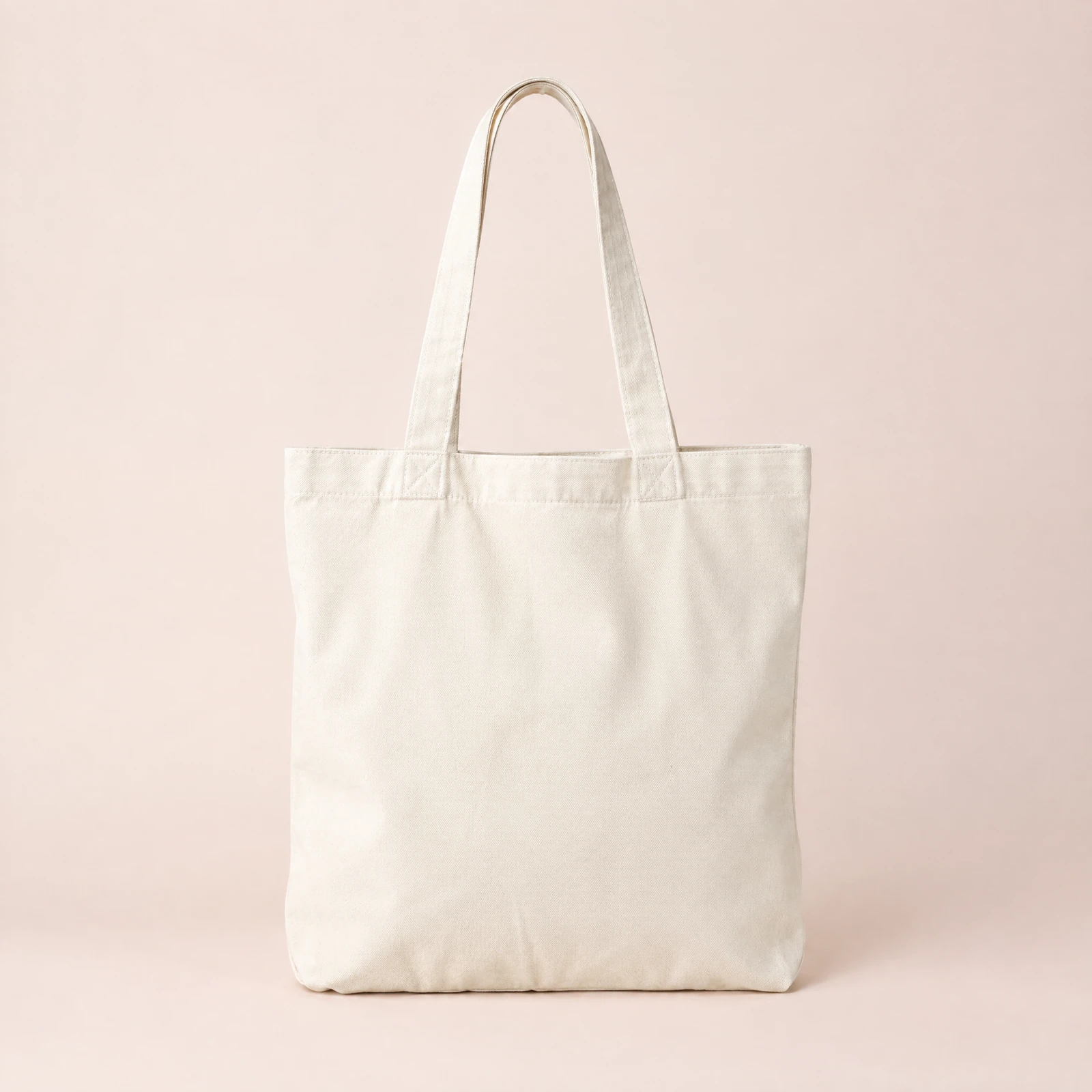 Plain natural off-white tote bag upright on a blush background