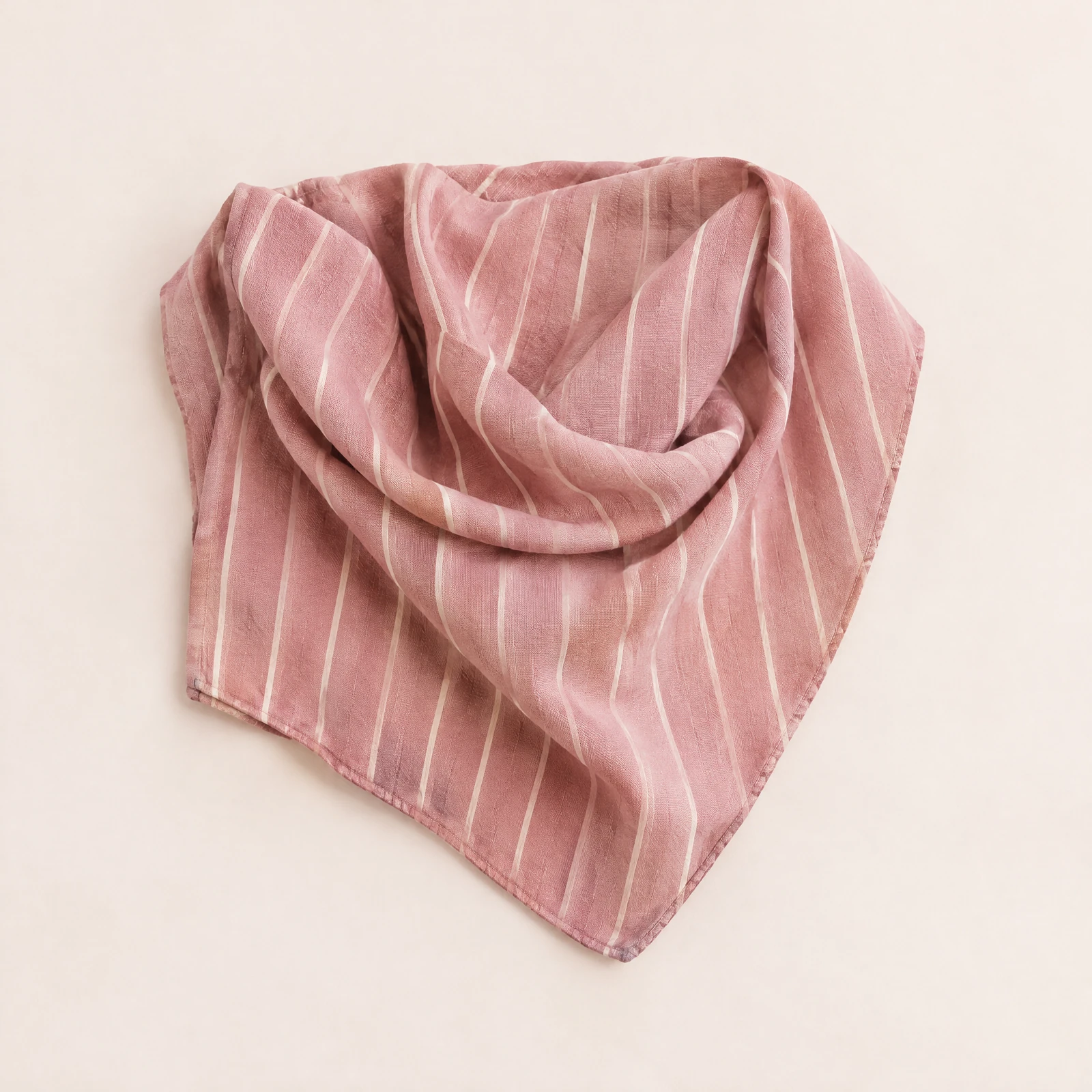 Folded dusty rose scarf with cream stripes on a blush background